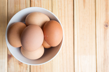 hen eggs in bowl on wood plate