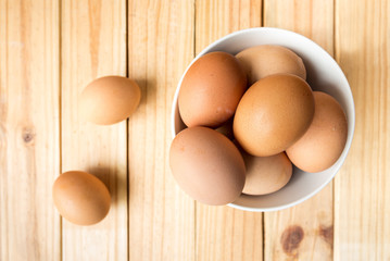 hen eggs in bowl on wood plate