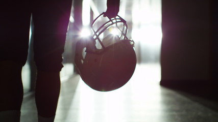 American football player walks alone through stadium tunnel - Powered by Adobe