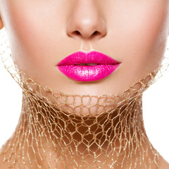 Female lips with pink lipstick and golden veil on the neck. clos