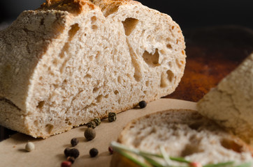 Half of bread on dark background with peper add rosemary close up.