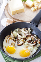 Scrambled eggs with mushrooms to frying pan, sliced cheese and herbs