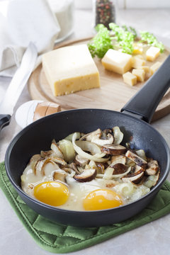 Scrambled eggs with mushrooms to frying pan, sliced cheese and herbs