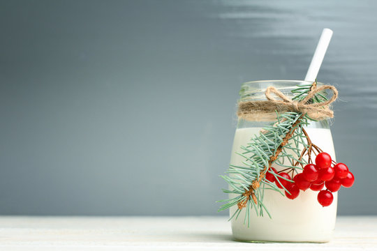 a jar of milk and viburnum  with fir twig on wooden background