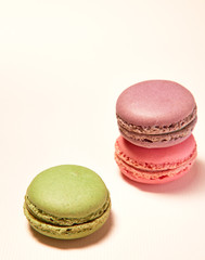 Purple, pink and green macarons on pink background.