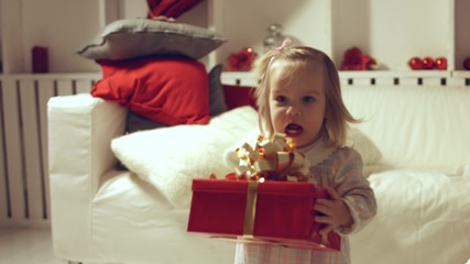 Baby wearing in dress going with a big gift in her hand