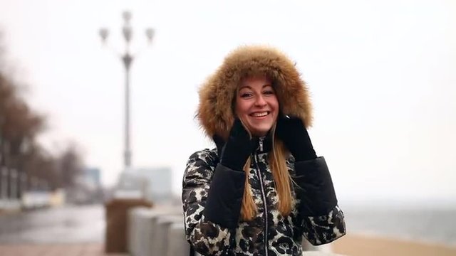 young beautiful girl in winter jacket with fur hood outdoors