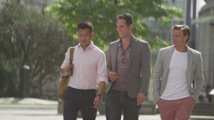  Happy casual male friends chatting as they walk through the city