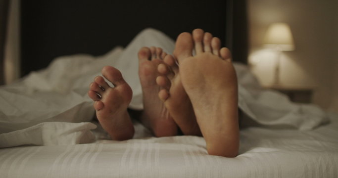  Happy feet of sexy couple in bed together. 