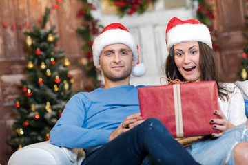 Fototapeta na wymiar Great Christmas surprise. Couple in love is sitting in festive C