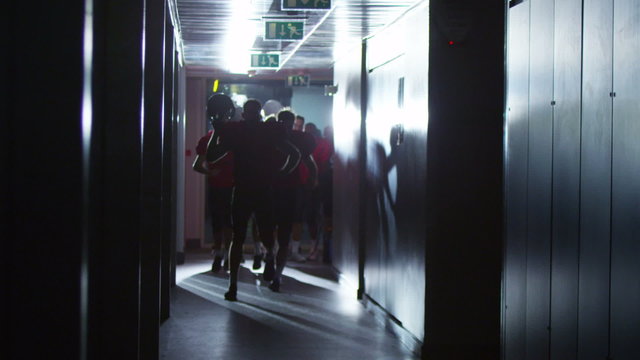 Excited American football team celebrate a victory as they run through tunnel
