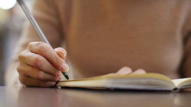  Attractive female student writing in her diary at a train station