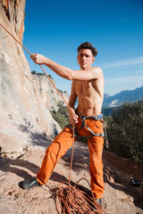 Rock climber collecting belay rope over the mountains