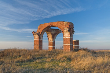 Fototapeta na wymiar Brick arches of old church ruins solitary in the field. 
