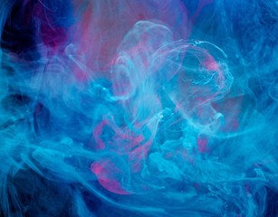 Smoky blue and pink ink in motion on water isolated on black