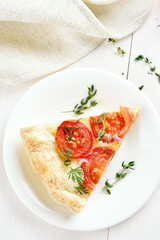 Piece of tomatoes pie on white plate