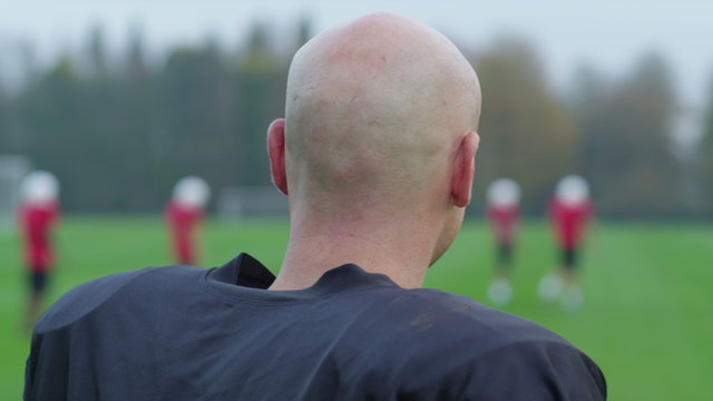  Portrait of smiling American football player watching the rest of his team