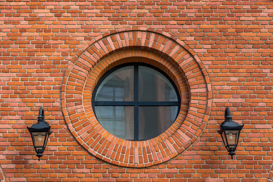 Beautifully renovated wall of an old textile factory with round window and two lanterns