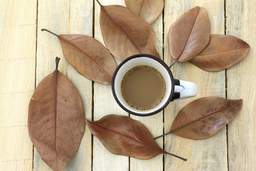 Autumn leaves and coffee cup over wood background