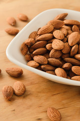 Healthy snack almond kernels in white bowl
