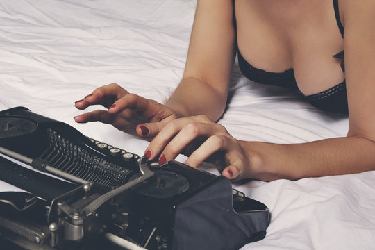 femme en lingerie écrivant couchée avec machine à écrire vintage