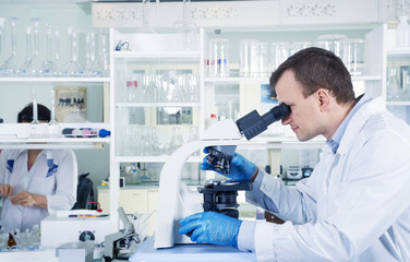 Scientist looking through microscope in laboratory