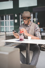 young handsome afro black man sitting on a table, smartphone han