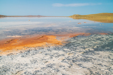 Salt pond with orange stains and clear blue sky