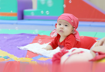 baby looking at soap bubble in colorful playroom