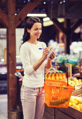 happy woman with food basket and notepad in market