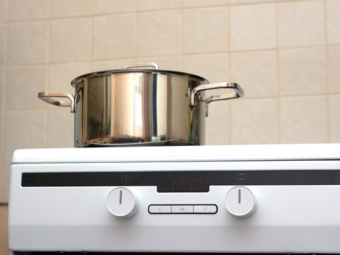 Metal steel saucepan with lid on new modern glass and ceramics kitchen electric stove. Photo closeup