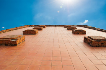 The red tile floor with brick and blue sky in background