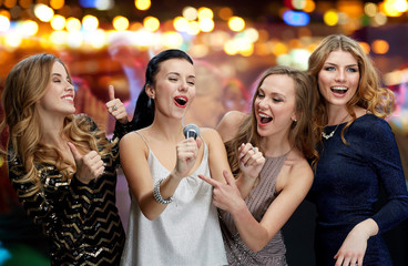 happy young women with microphone singing karaoke - obrazy, fototapety, plakaty