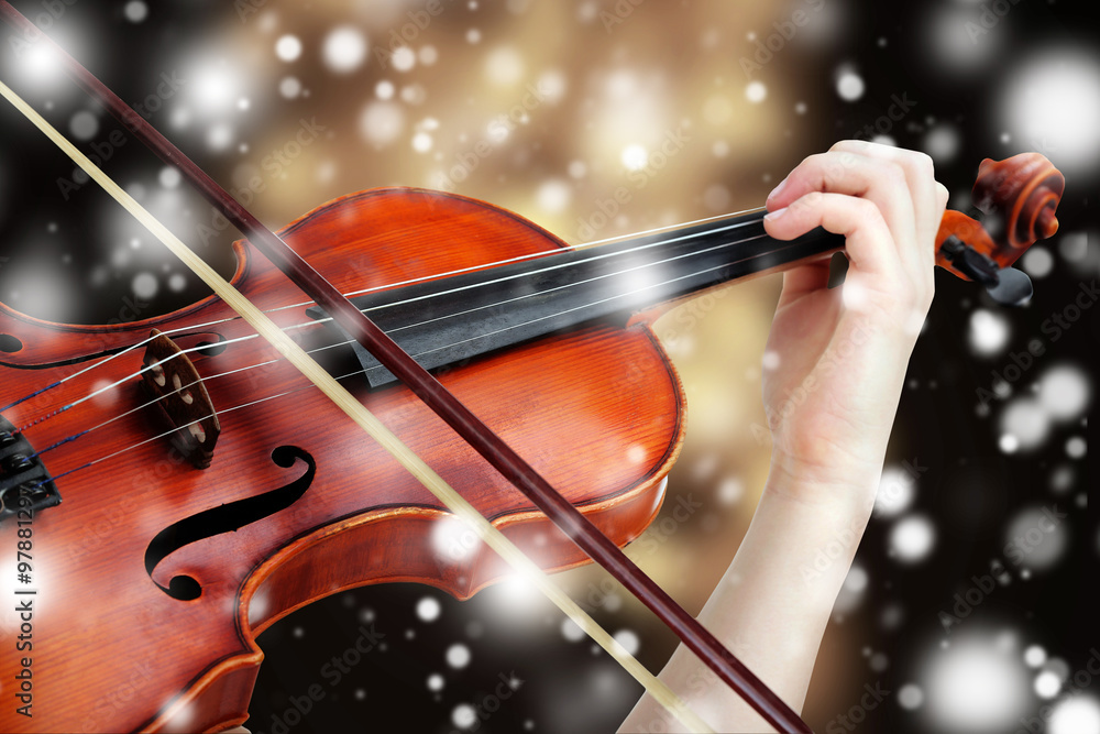 Wall mural beautiful young girl with classical violin on bright background over snow effect