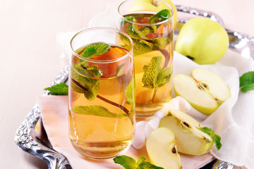 Glasses of apple juice with fruits and fresh mint on table close up