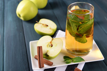 Glass of apple juice with fruits and fresh mint on table close up
