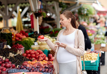 pregnant woman with smartphone at street market