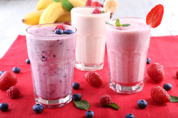 Milkshakes with berries at red textile on light background