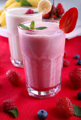 Milkshakes with berries at red textile on light background, close-up
