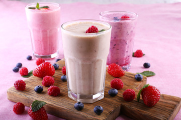 Milkshakes at cutting board with berries on light background