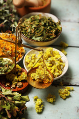 Assortment of dry medicinal herbs in bowls on wooden background top view