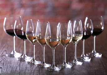 Wineglasses with white, red and pink wine on wooden table close-up