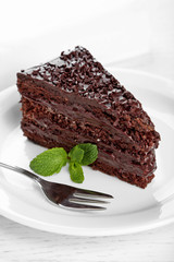 Chocolate cake with chocolate cream on plate, on light background