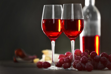 Two wineglasses with grape on the table over dark background, close-up