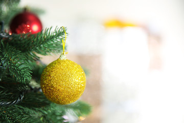 Christmas golden bauble on a fir tree over blurred background, close-up