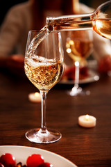 Pouring white wine from bottle into the wineglass