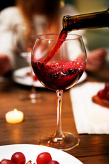 Pouring red wine from bottle into the wineglass