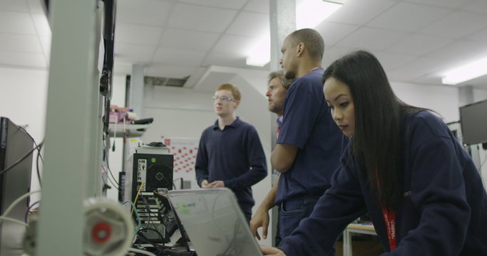 Team of workers in an electronics factory working on computer testing and repair