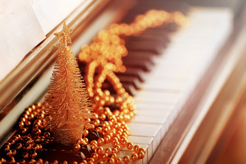 Piano keys decorated with golden Christmas decorations, close up