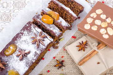 Chcolate spices cake with star anise and dried fruits, cinnamon, cloves, cardamom, handmade milk chocolate with nuts on sackcloth, canvas. Christmas gift.